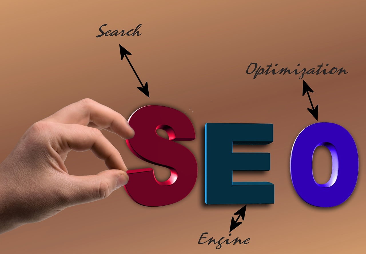 一只手拿着棕色背景上的“SEO”一词，强调网站建设对于有效品牌营销的重要性。